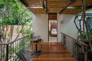 A wooden deck with a table and chairs, a bed in the background, and a view of trees and a fence. - TreeHouse Boutique Hotel - Adults Only  (Mérida)