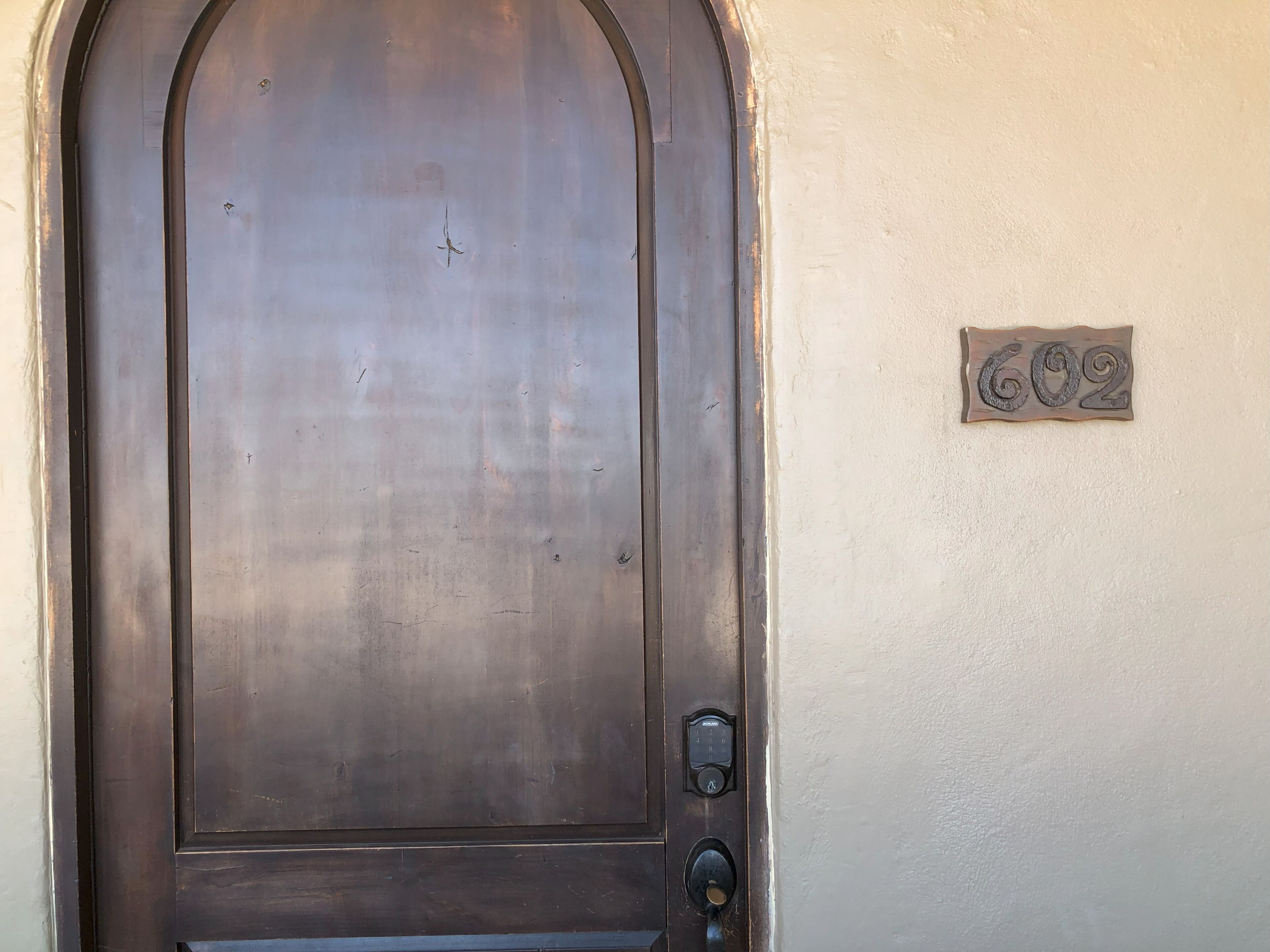 A dark wooden door with a metal handle and a keyhole. A small plaque with the number "602" is mounted on the wall to the right of the door.