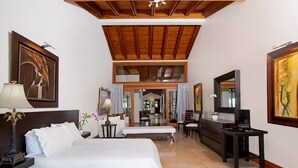 A spacious hotel room with a large bed, a desk, a television, and artwork on the walls.
