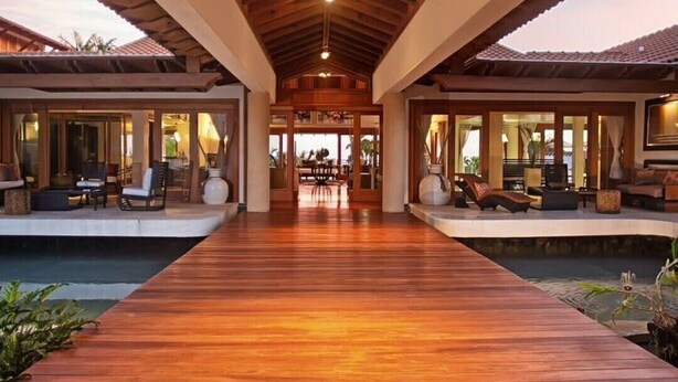 A wooden deck leading to a pool area with outdoor seating and a covered dining area.