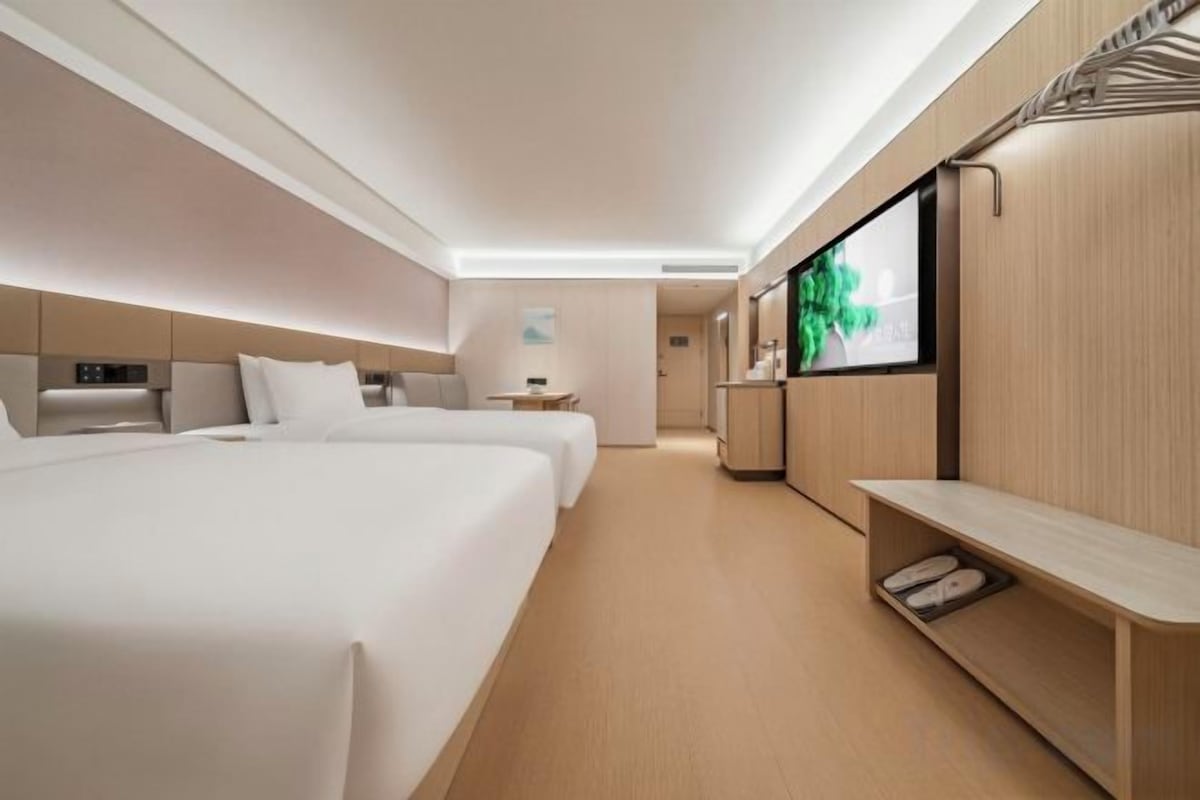 A hotel room with two beds, a TV, a desk, and a seating area.