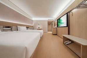 A hotel room with two beds, a TV, a desk, and a seating area.