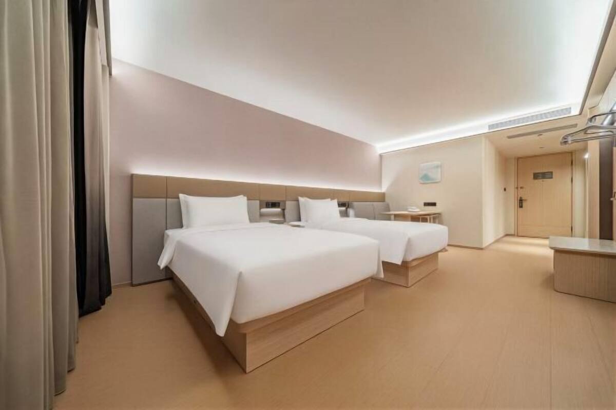 Habitació d'hotel amb dos llits, una taula de nit, un escriptori petit i un armari.