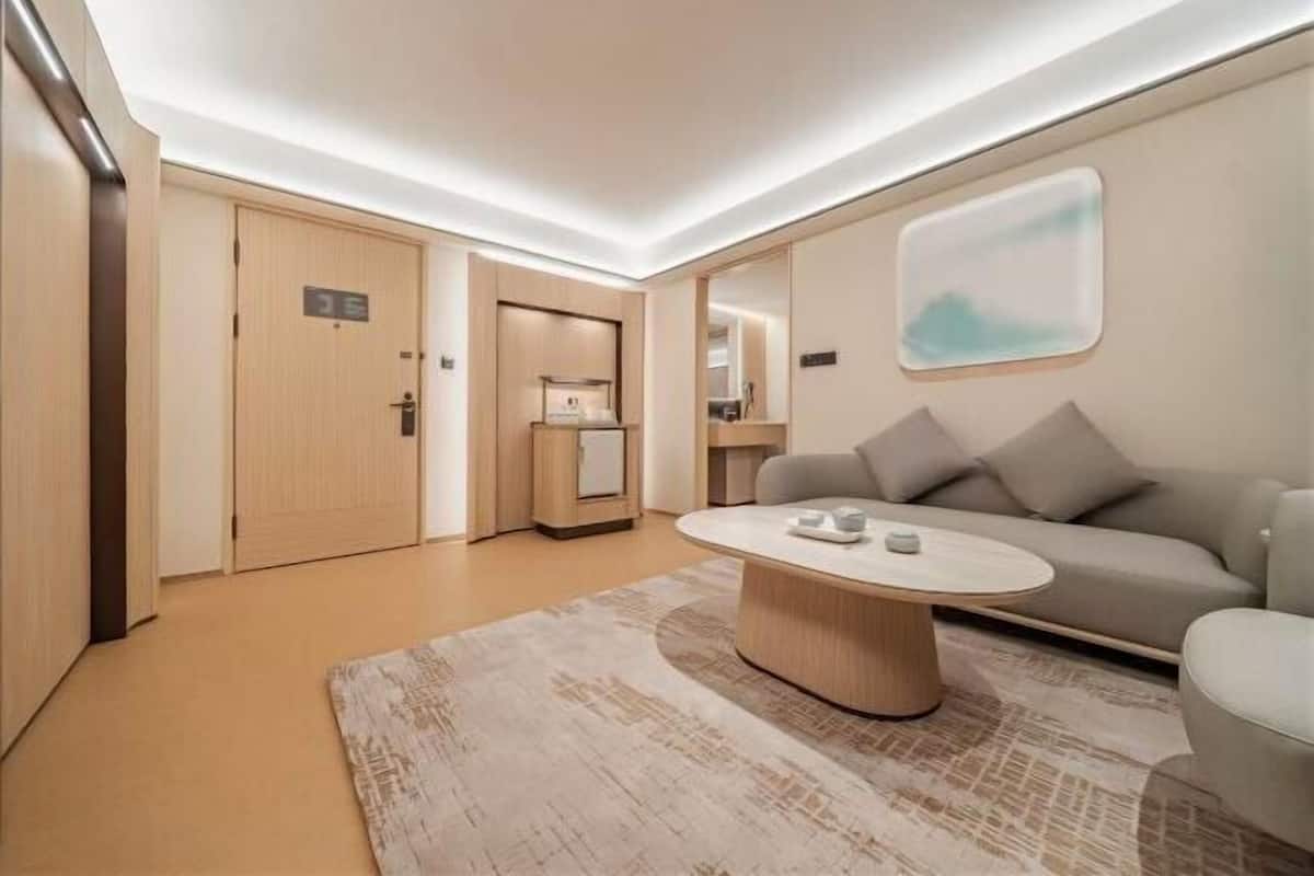 Habitació d'hotel moderna amb una taula de cafè rodona, un sofà i un gran mirall.