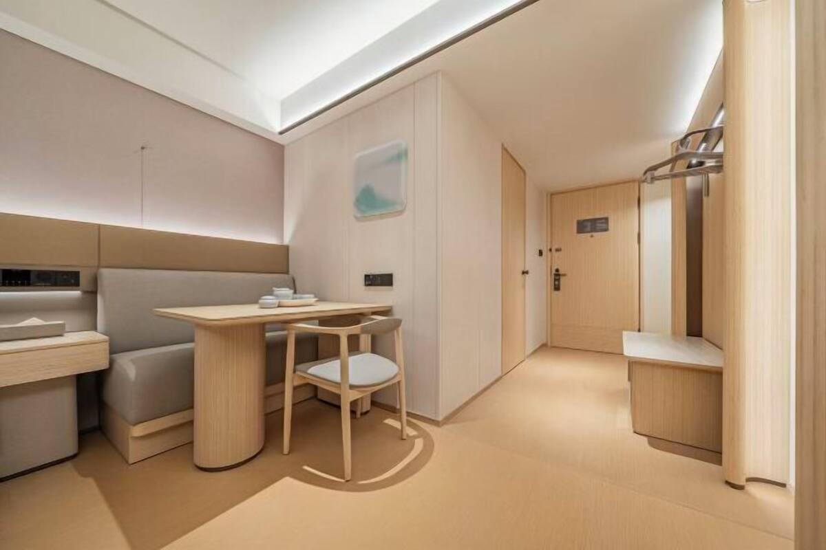 Habitació compacta i moderna amb disseny minimalista, que inclou una taula petita, una cadira, un sofà i un armari.