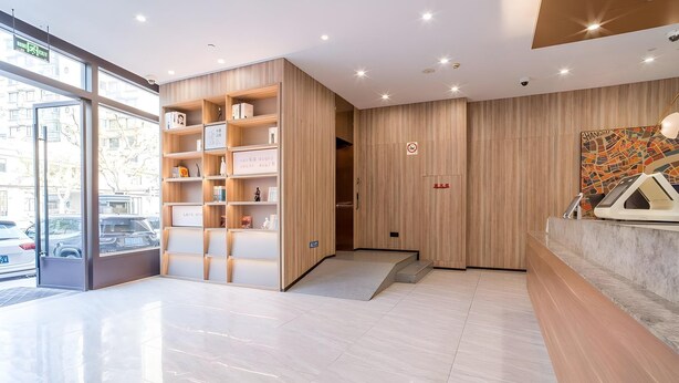 A modern hotel lobby with a wooden reception desk, a glass door entrance, and a cityscape view. - Hanting Hotel (Shanghai)