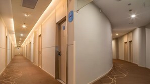 A long, well-lit corridor with doors on both sides, leading to individual rooms. - Hanting Hotel (Shanghai)