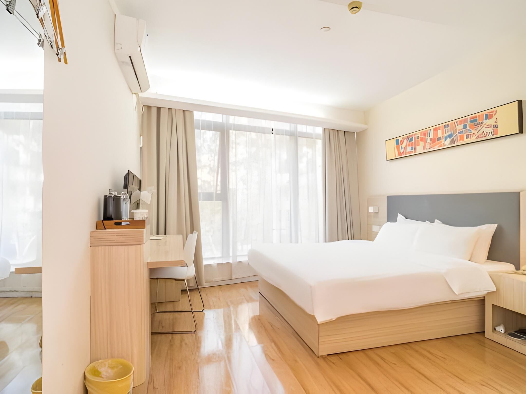 A modern hotel room with a large bed, a desk, and a chair.
