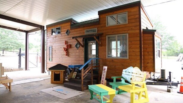 A wooden cabin with a covered porch, a small staircase, and outdoor seating. - Secluded Wooded Charmant Chalet  "Theme"  Tiny Home - Off Grid (Aylette)
