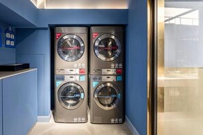 A laundry area with four stacked washing machines, each marked with a 13KG capacity.