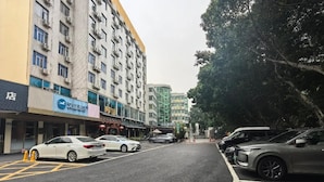 A street view with a row of parked cars, a building with multiple floors, and a tree-lined sidewalk. - Hanting Hotel Guangzhou Tianpingjia Metro Station (Guangzhou)