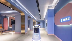 A modern hotel corridor with a self-service kiosk, a seating area, and a digital display on the wall. - Hanting Hotel Guangzhou Tianpingjia Metro Station (Guangzhou)