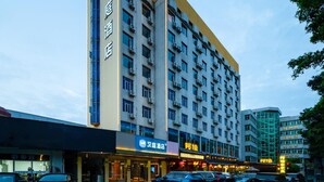 A multi-story hotel with a prominent sign on the facade, multiple windows, and a parking lot with cars. - Hanting Hotel Guangzhou Tianpingjia Metro Station (Guangzhou)