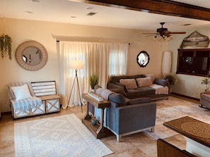 A living room with a sofa, armchairs, a coffee table, a floor lamp, and a large mirror.