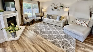 A living room with a fireplace, a sofa, two armchairs, a coffee table, and a patterned rug.