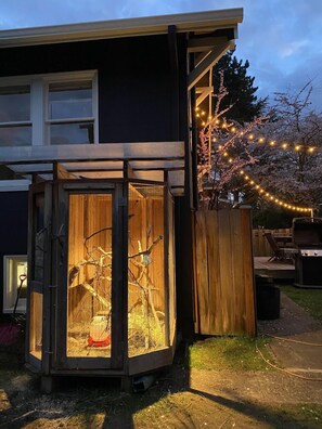 A wooden structure with a mesh enclosure, a barbecue grill, and a string of lights in a backyard. - Adorable Farm Stay in Ballard! Bunnies, A/C, walkable, near beach & attractions (Seattle)
