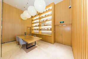 Un salón de conferencias con una mesa de madera, sillas, una estantería y una cámara de seguridad.