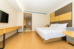 Una habitación de hotel con cama, escritorio, televisor y una mesita.