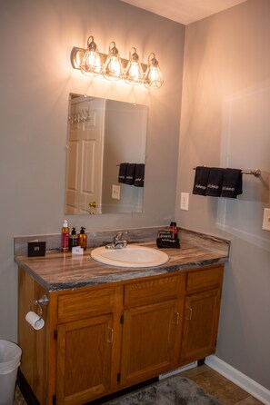 Une salle de bain avec un meuble-lavabo en bois, un évier, un miroir et un porte-serviettes avec des serviettes.