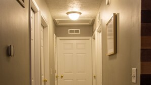 En hall med trägolv, vita dörrar och en lampa i taket.