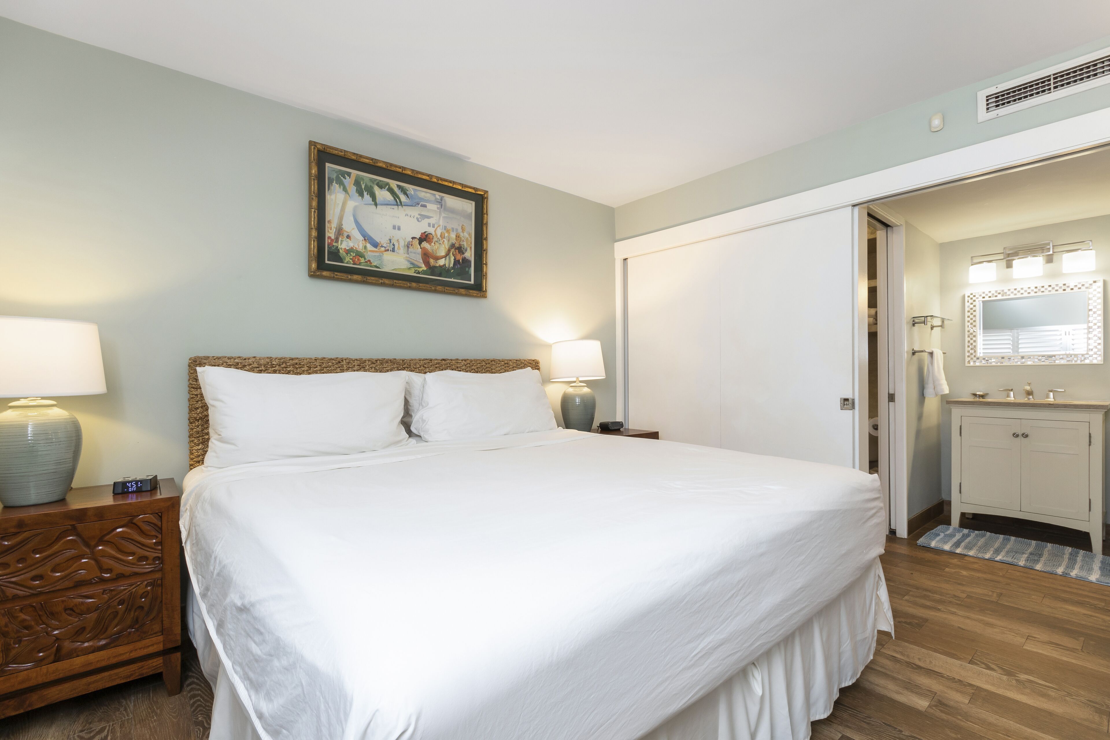 Un lit bien fait, avec des draps blancs, une tête de lit en bois et deux lampes de chevet.
