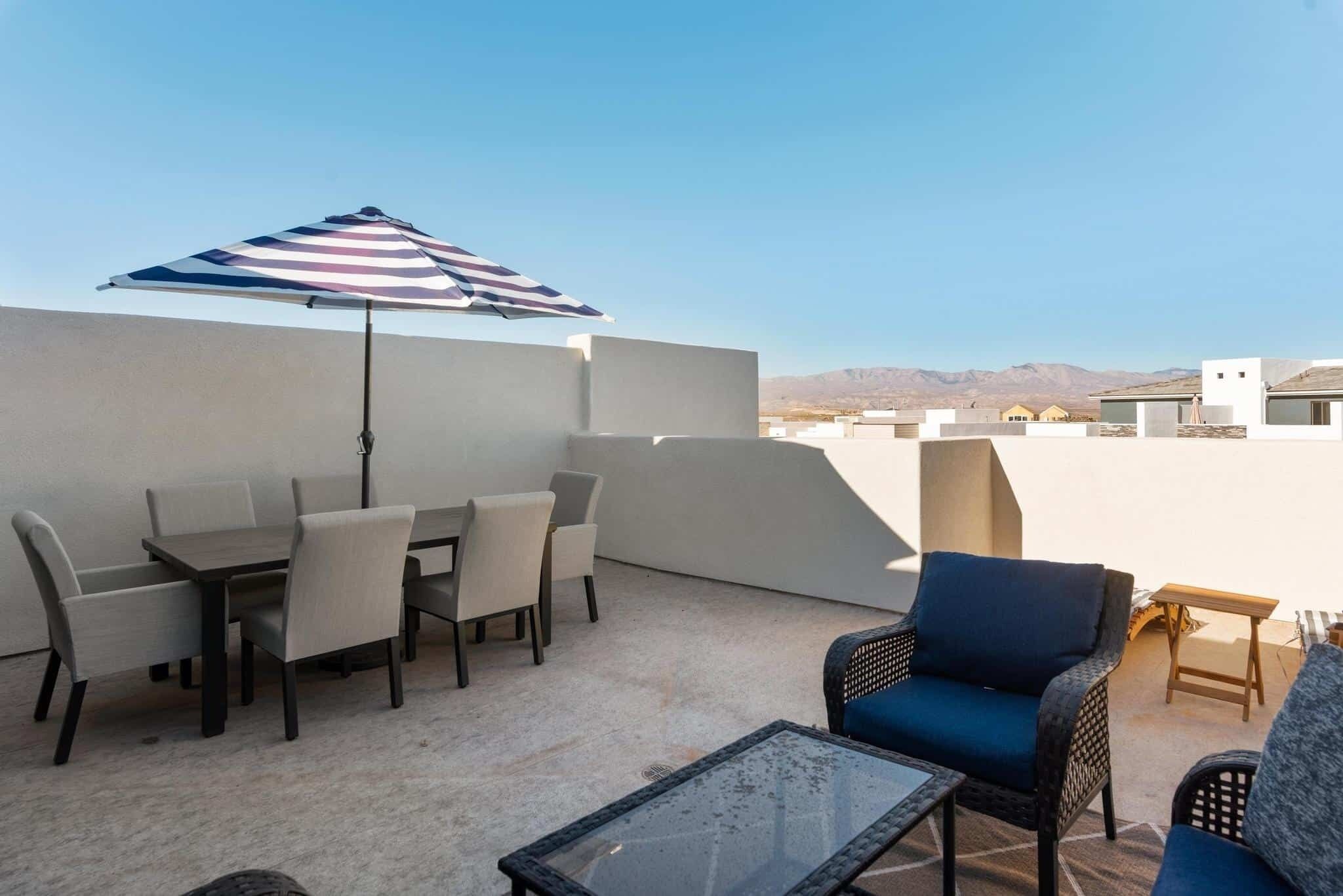 A rooftop patio with a table and chairs, a glass table, and a wicker chair.