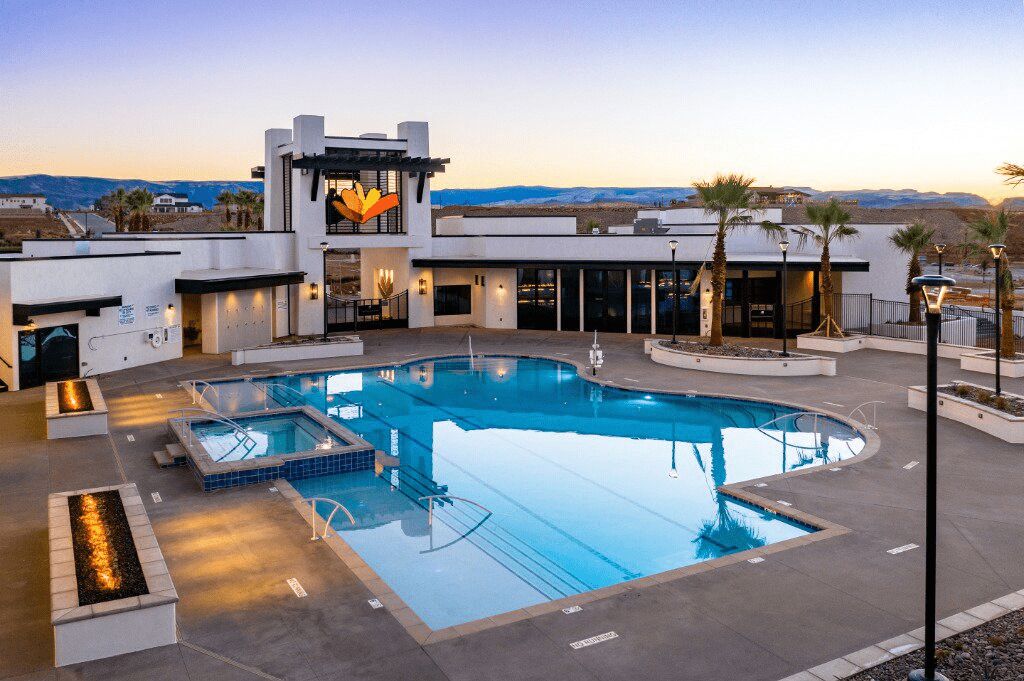 Et moderne hotel med en stor udendørs swimmingpool, et overdækket opholdsområde og udsigt til bjergene.