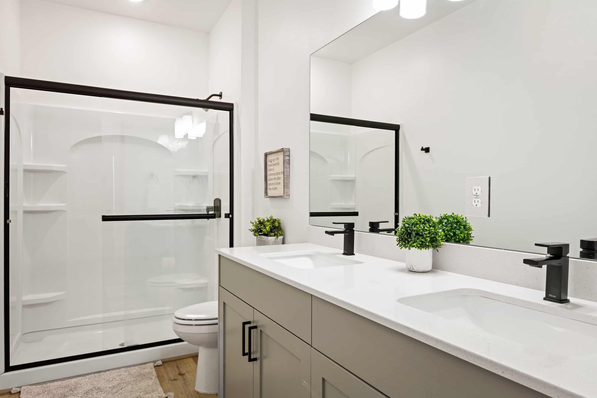 A modern bathroom with a glass shower enclosure, two sinks, and a large mirror.