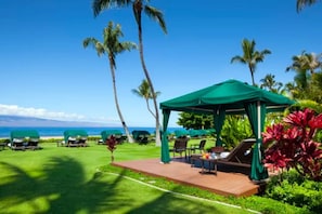 A covered outdoor seating area with chairs and tables, overlooking a beach. - World Class Resort Marriott Maui Ocean Club Ground Floor Ocean Front 3 bd 3bth (Lahaina)