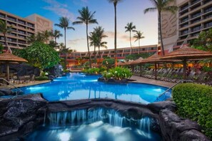 A hotel pool area with a waterfall feature, palm trees, and lounge chairs. - World Class Resort Marriott Maui Ocean Club Ground Floor Ocean Front 3 bd 3bth (Lahaina)