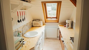 Cocina compacta con ventana, encimeras de madera, un lavamanos y electrodomésticos básicos.
