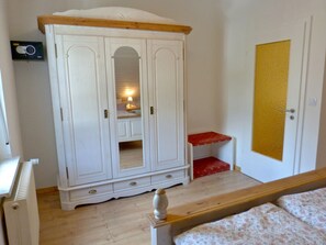 A room with a white wardrobe, a wooden bed, a red bench, and a door with a yellow panel. - Lovingly guest apartments Alpirsbach - Apartment 3 (Alpirsbach)