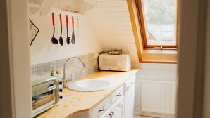 Una cocina con un lavamanos blanco, un tostador y una ventana sobre el lavamanos.