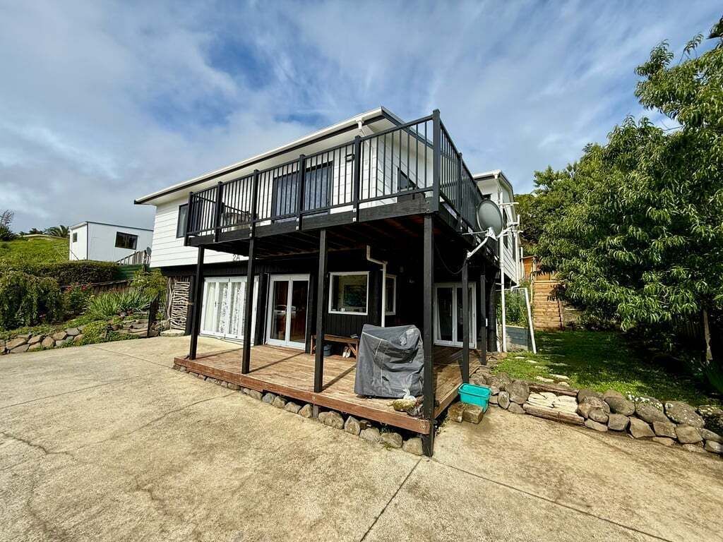 A two-story house with a balcony, a satellite dish, and a covered outdoor area.
