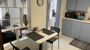 Cocina compacta con comedor, que incluye un reloj, un ventilador y un microondas.
