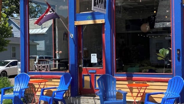 Fachada de una tienda con pintura azul, con el número 197, y un letrero que indica que está abierta.
