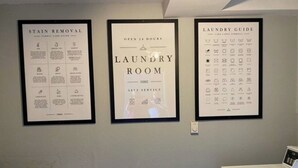Un lavadero con zona de autoservicio, una guía para quitar manchas y un manual de lavandería en la pared.