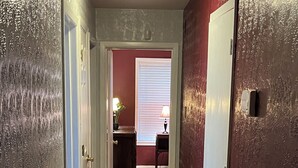 A hallway with a tiled floor, a door on the right, and a window with blinds in the background. - The Ranger House, 5 minutes to TAMU campus, quiet street, large fenced backyard (Bryan)