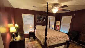 A bedroom with a four-poster bed, two bedside tables with lamps, a ceiling fan, and a large mirror. - The Ranger House, 5 minutes to TAMU campus, quiet street, large fenced backyard (Bryan)