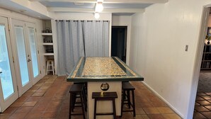 A kitchen with a tiled floor, a central island with stools, and a window with blinds. - The Ranger House, 5 minutes to TAMU campus, quiet street, large fenced backyard (Bryan)