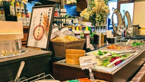 Zona de bufé con diferentes alimentos, salsas y un letrero con texto en japonés.