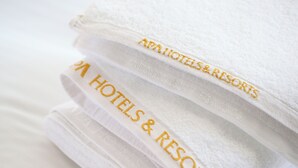 Una pila de toallas blancas con el texto bordado que dice "AAA HOTELS & RESORTS".