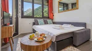 Une chambre avec un lit, une télévision, une table avec des pâtisseries et une vue sur les montagnes.