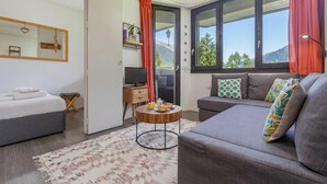 Une chambre moderne équipée d’un lit, d’un canapé, d’une télévision et d’une table à manger où sont servis des plats.
