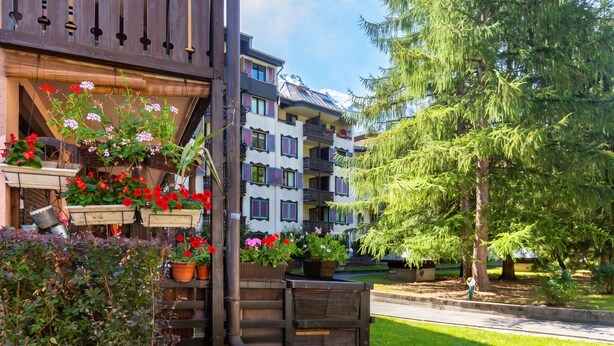 A multi-story building with balconies, potted plants, and a well-maintained lawn. - Cham Sud Grepon102 Mountain-View Balcony for 4, Chamonix, France (Chamonix)