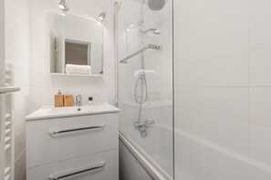 A modern bathroom with a glass-enclosed shower, a white sink with a mirror above it, and a wooden vanity with drawers. - Cham Sud Grepon102 Mountain-View Balcony for 4, Chamonix, France (Chamonix)
