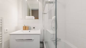 Een bad/douchecombinatie, een haardroger, handdoeken