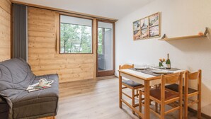 A wooden interior with a sofa, dining table, chairs, and a large window. - Cham Sud Grepon102 Mountain-View Balcony for 4, Chamonix, France (Chamonix)