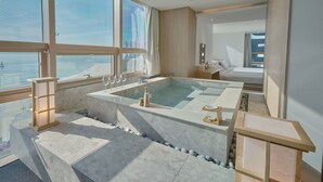 Une salle de bain moderne dotée d’une grande baignoire, d’un coin salon et offrant une vue sur la ville.