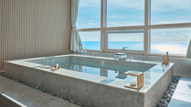 Une salle de bain moderne avec une grande baignoire, une vue sur la mer et un mur en bois.